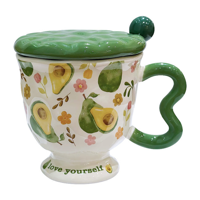 Aesthetic cream ceramic pedestal mug with green avocado and floral patterns, featuring a green wavy handle and a text "love yourself" on the footed base. Includes a green textured ceramic lid with a ball knob, shown on a white background. Hover Image